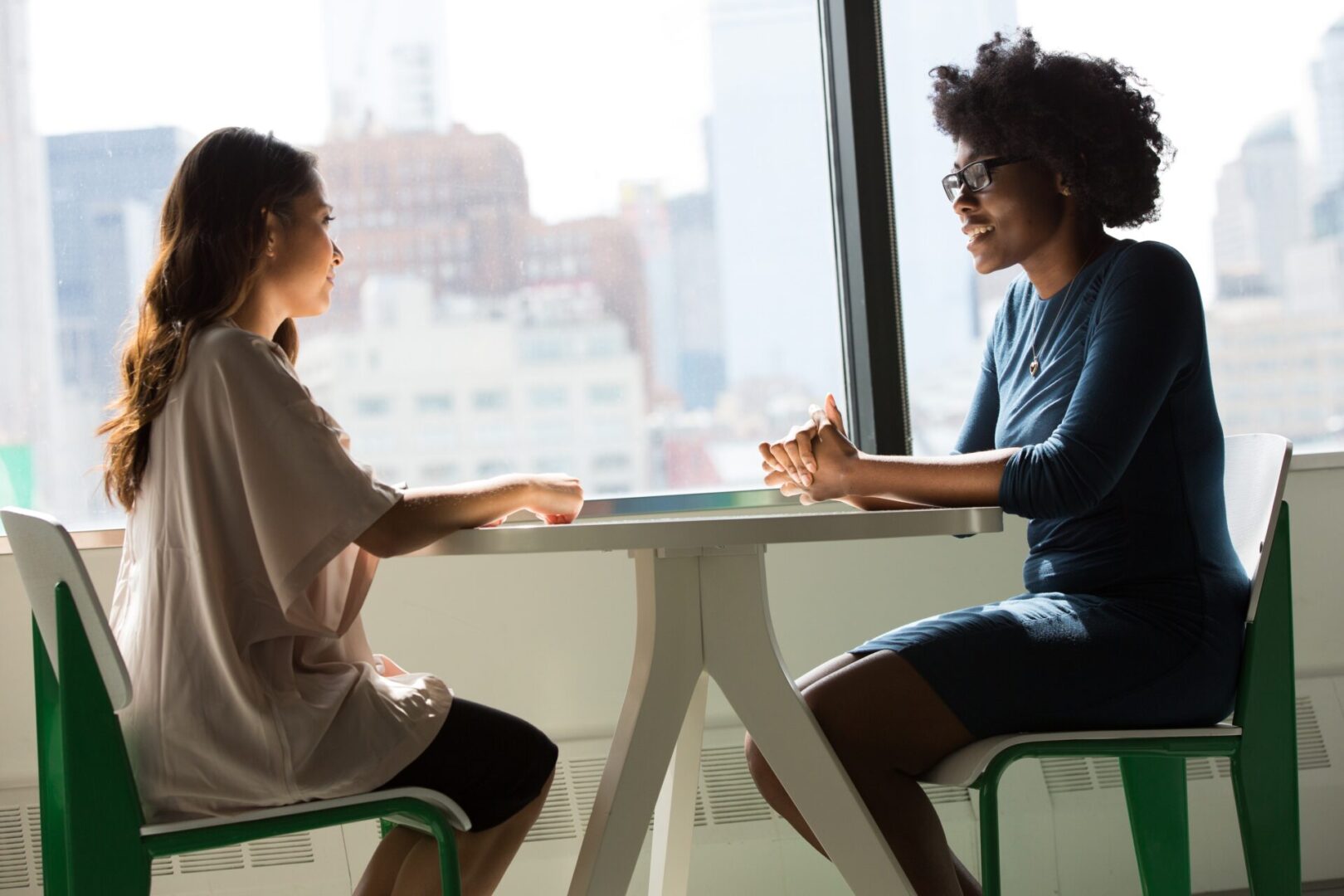 Two women sitting at a table in front of a window.